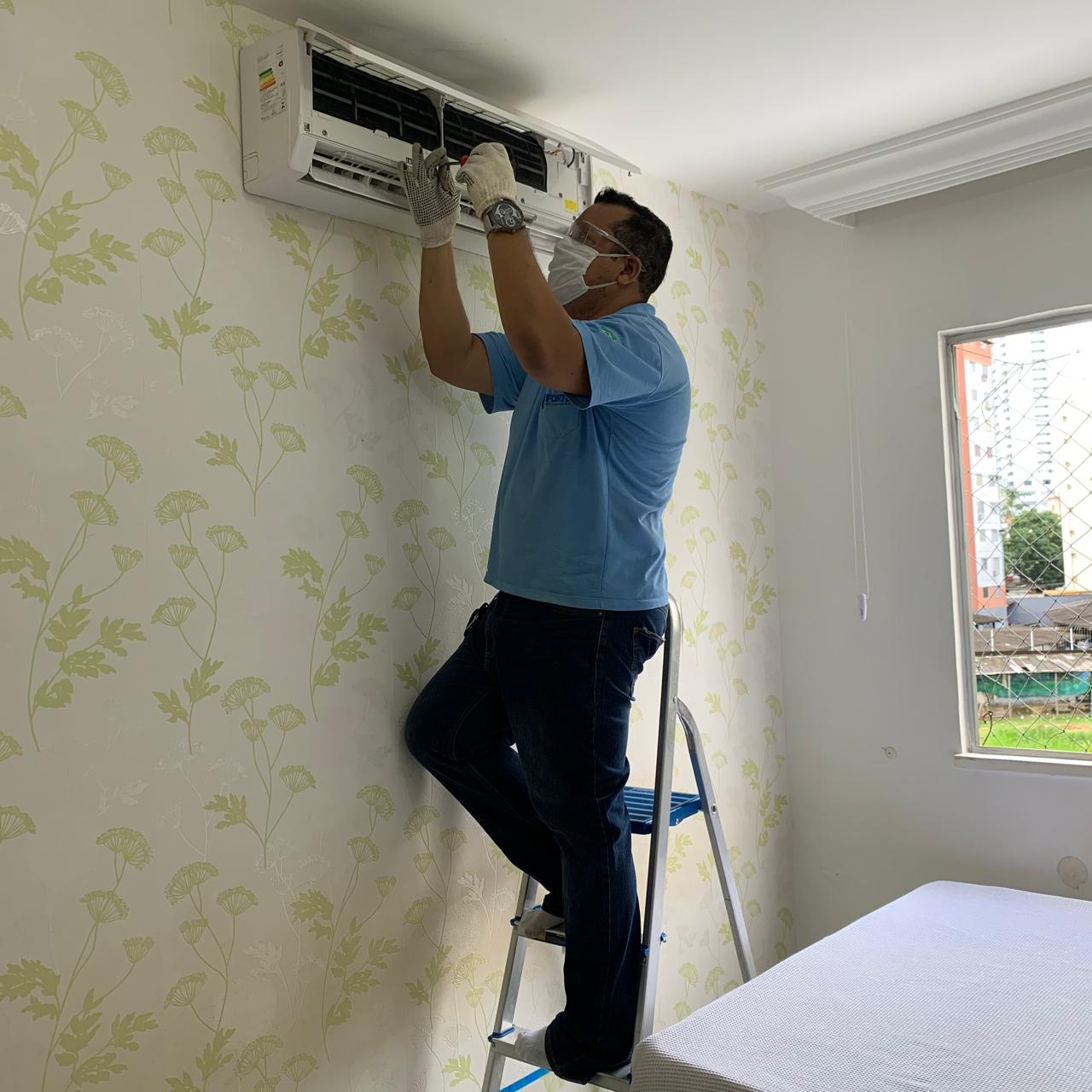 Técnico com EPI fazendo manutenção e higienização de ar-condicionado split